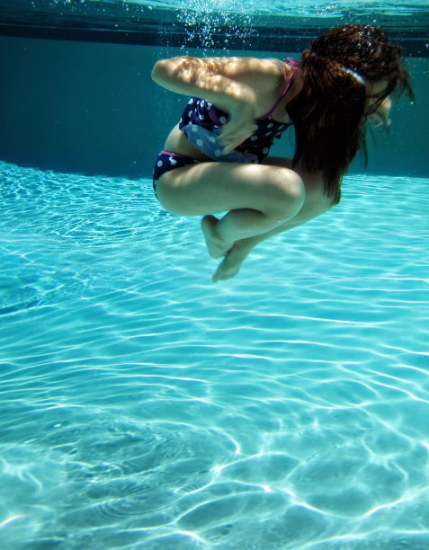 在游泳池游泳的小女孩的水下图像图片下载