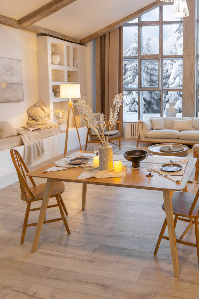 舒适温暖的家庭内部别致的乡村小屋与一个巨大的全景窗口俯瞰冬季森林。开放式布局，木质装饰，暖色调和家庭壁炉图片下载