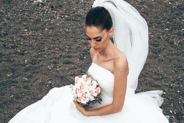 幸福的新娘穿着白色礼服坐在沙滩上图片下载