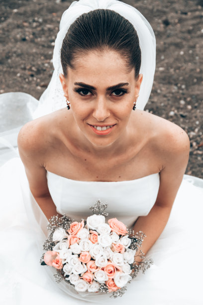 幸福的新娘穿着白色礼服坐在沙滩上图片下载