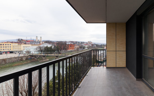 多层建筑的宽阔阳台，有时尚的黑色金属栏杆。阳台俯瞰河流。图片下载