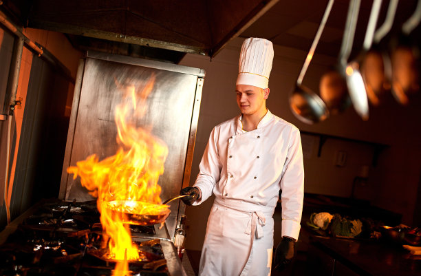 Сhef在专业厨房用一个煎锅和一个火图片下载