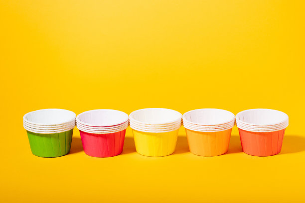 在黄色背景上制作松饼和纸杯蛋糕的彩色纸模具图片下载