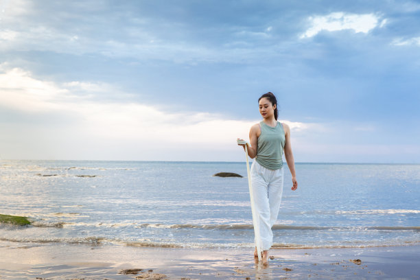 年轻的女士练习伸展使用一个阻力带在海滩-股票照片图片下载