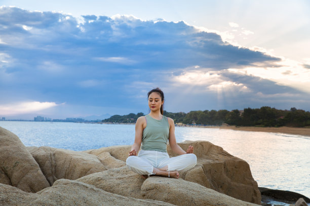 美丽的年轻女士练习瑜伽在海滩礁石-股票照片图片下载