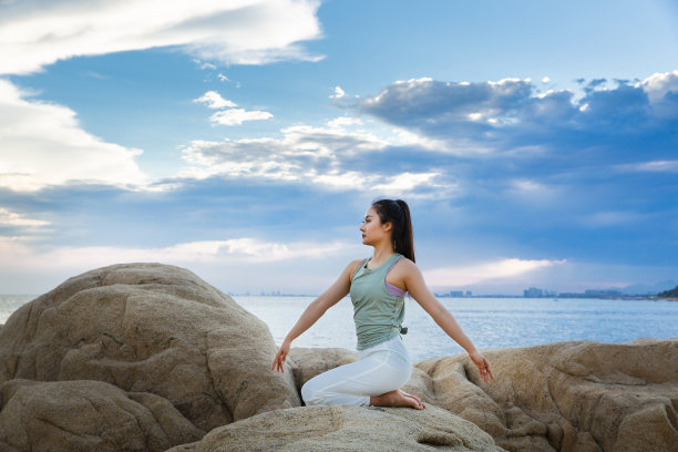 美丽的年轻女士练习瑜伽在海滩礁石-股票照片图片下载