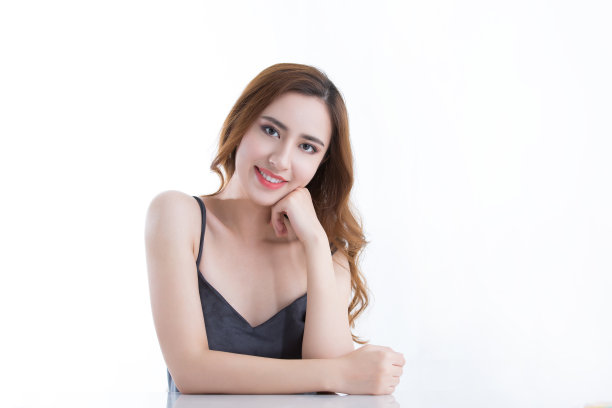 美丽的年轻中国女士看相机与她的下巴在她的手，在白色背景-股票照片图片下载