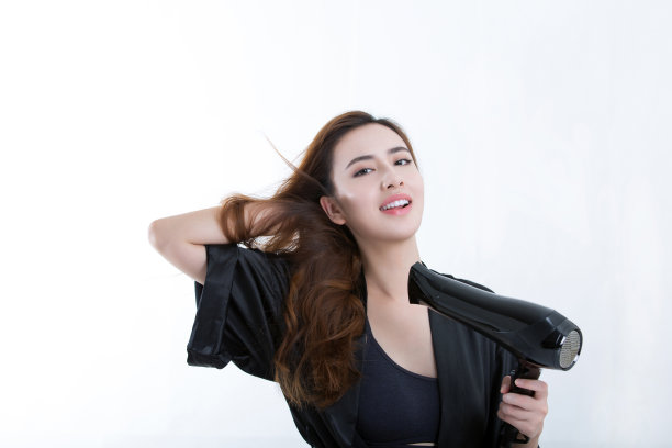 年轻美丽的中国女人用吹风机吹干头发，在白色背景- stock照片图片下载