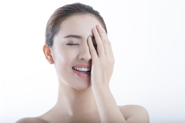 年轻的女士抚摸她的脸与她的眼睛闭上，感觉她的皮肤的水分，在白色背景-股票照片图片下载