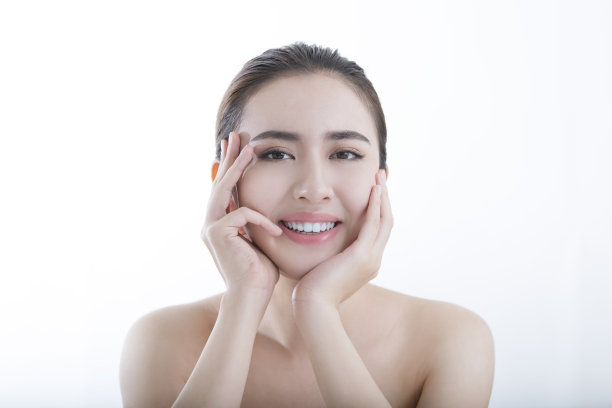 在一张白色背景照片上，一位做过面部拉皮手术的年轻女士抚摸着她的脸颊，感觉到皮肤上的水分图片下载