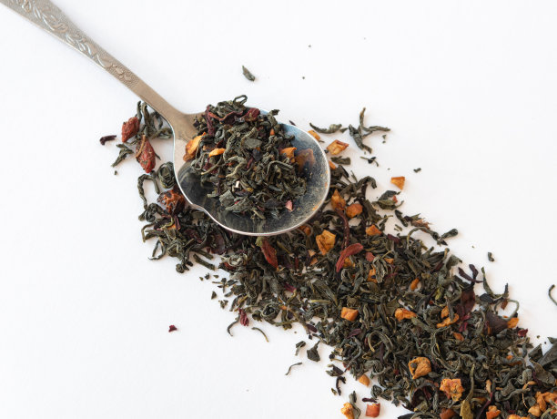 用勺子和绿茶，水果片和草药叶子撒在白色上图片下载