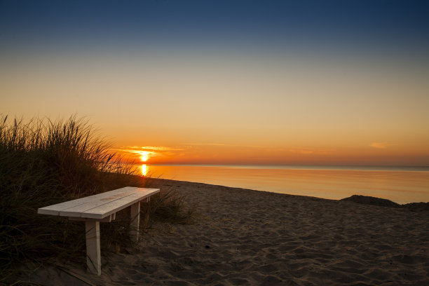 日出时沙滩上的长椅图片下载
