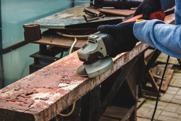 一个男人正在磨一块木板。清除木板上的旧漆。木工工作。图片下载