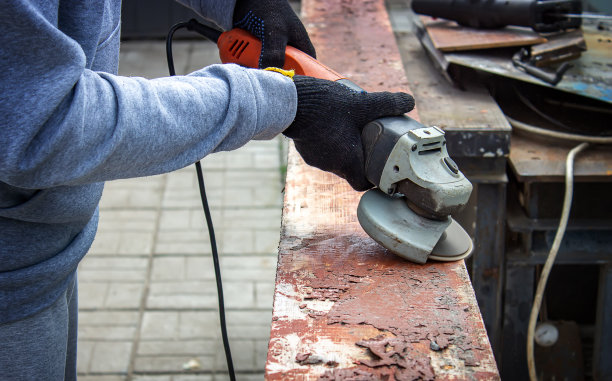 一个男人正在磨一块木板。清除木板上的旧漆。木工工作。图片下载