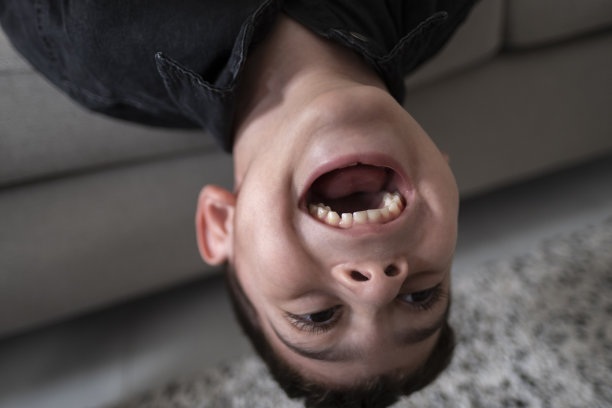 小男孩在家里的沙发上倒立，顽皮地玩耍图片下载