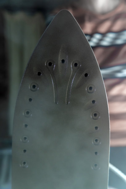 一个家庭主妇手里拿着一个热气腾腾的熨斗。洗衣女工正在烫衣服。现代生活方式的概念，一个在家熨衣服的女人图片下载