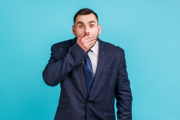 我不会说的。惊讶的商人穿着正装，用手捂住嘴，保守秘密，对令人震惊的消息感到恐惧。图片下载