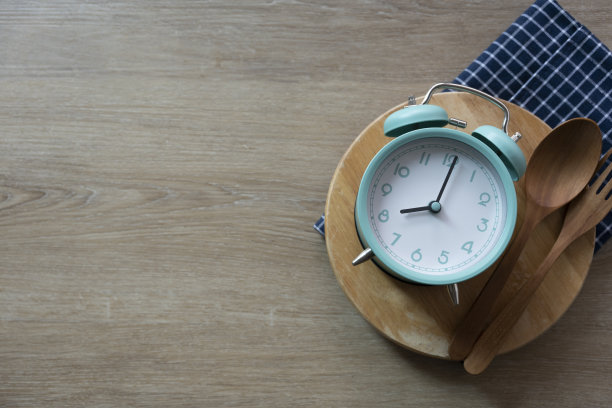 食物钟勺子和叉子，木制餐桌背景上的健康食物早餐概念图片下载