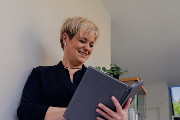 一个成熟的金发女人看着她的平板电脑的肖像。工作中的女商人。图片下载