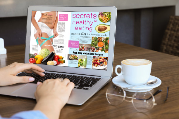 在咖啡馆用笔记本电脑看网络杂志的女人，特写图片下载