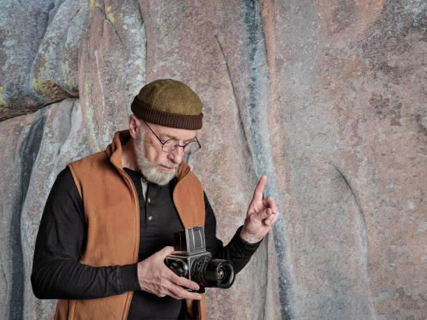 一位手持旧相机的资深男性摄影师的肖像图片下载