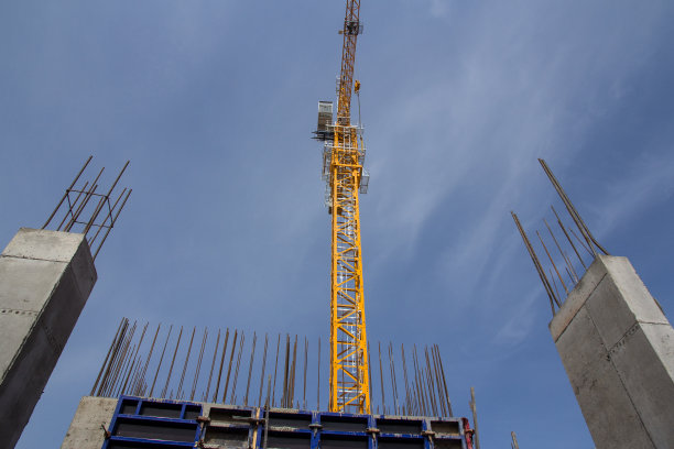 塔吊及建筑物混凝土基础。以天空为背景的施工起重机。图片下载