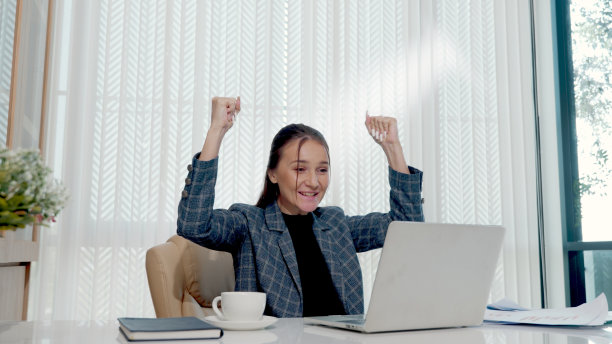 快乐的商业女人兴奋惊讶的工作在白色的办公桌与pc笔记本电脑扔纸帐户文件图片下载