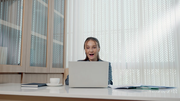 快乐的商业女人兴奋惊讶的工作在白色的办公桌与pc笔记本电脑扔纸帐户文件图片下载