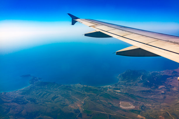 从飞机的窗口看，美丽的蓝天、大地、大海和飞机的机翼图片下载