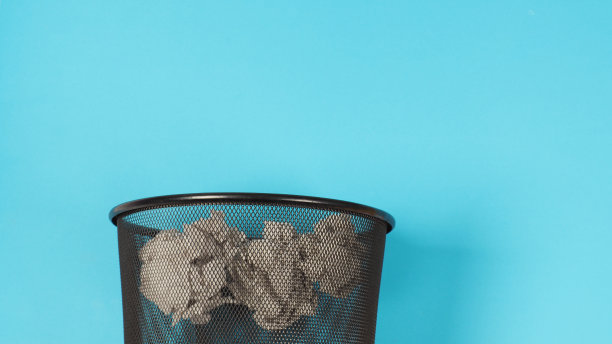 蓝色背景上皱巴巴的白纸垃圾桶的裁剪图片。图片下载