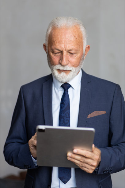 成熟的商人专注于iPad上的工作图片下载