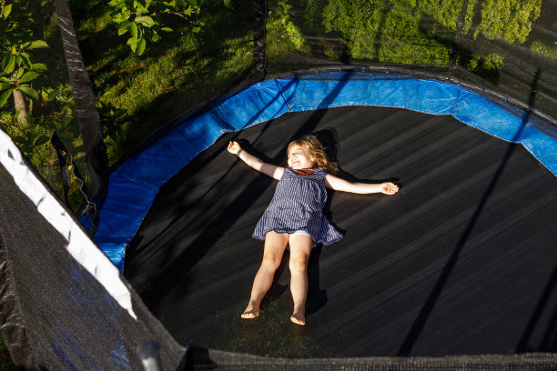 学龄前的小女孩在蹦床上跳。快乐有趣的蹒跚学步的孩子在夏天有户外活动的乐趣。儿童体育运动。图片下载
