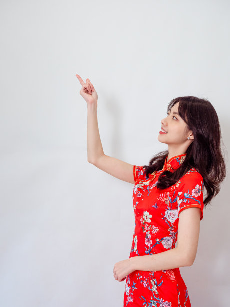 亚洲女子身着传统旗袍，用手指着旗袍，复制空间孤立在白色背景上。图片下载