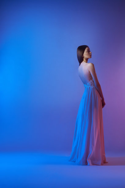 艺术时尚美丽优雅的女人在吹飞扬的裙子。霓虹灯中的自由概念。时尚风格的飘逸的衣服在身体的女人图片下载