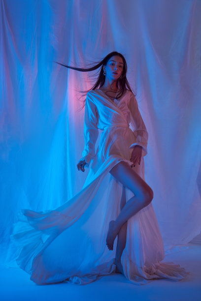 在演播室里穿着浅色连衣裙的时尚美女。霓虹灯下的自由音乐会。时尚风格轻裙适合身型女性，双腿修长图片下载