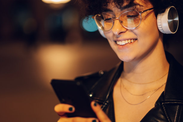 女人走在城市的街道上，戴着手机和耳机图片下载