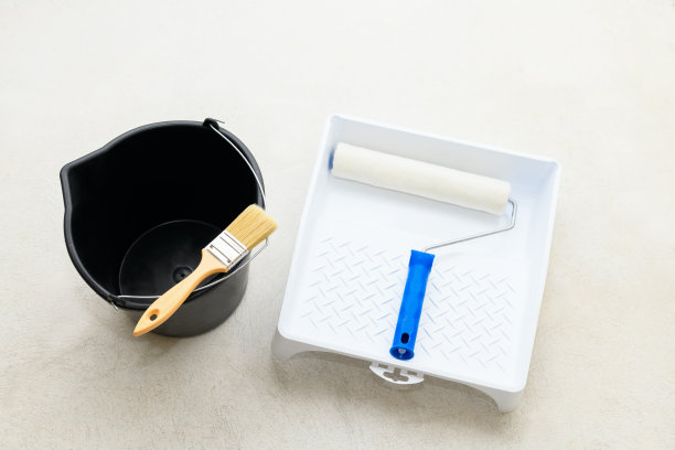 油漆组:托盘(浴槽)上的滚筒，混凝土地板上的刷子和空桶，特写。修理工具放在地板上图片下载