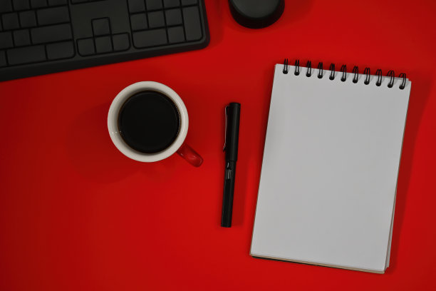 俯视图平坦的笔记本，键盘和一杯咖啡在红色背景上的空白空间的商业和技术概念。图片下载
