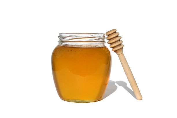新鲜液体蜂蜜在瓶子上白色孤立的背景图片下载