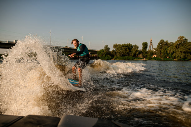 男子在冲浪板上飞溅的波浪和水滴周围图片下载