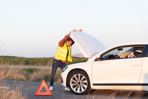 年轻男子在背心孤家寡人靠在一个开放的汽车引擎盖后，在农村的路边抛锚图片下载
