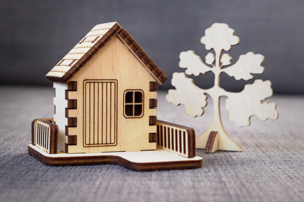 木制装饰玩具屋，有栅栏和灰色背景上的一棵树。图片下载