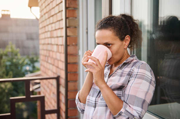 在阳台上喝咖啡的漂亮棕发女人图片下载