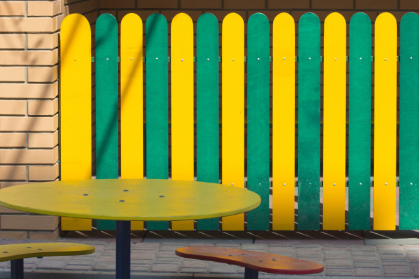 操场上的空桌子。隔离。五光十色的栅栏上，有一块广告牌题字。图片下载