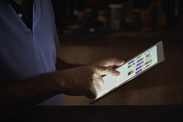 一名老年男子在家里的厨房里使用数码平板电脑图片下载