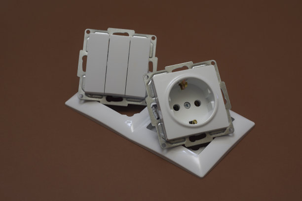 棕色背景上的家用塑料插座和电源开关。图片下载