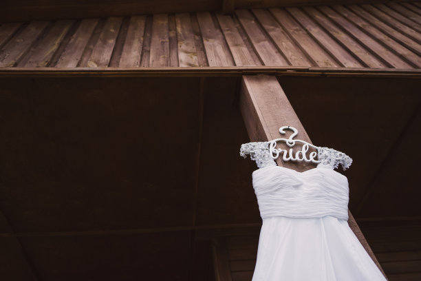 特写白色婚纱在定制的木制衣架上的木制背景。图片下载