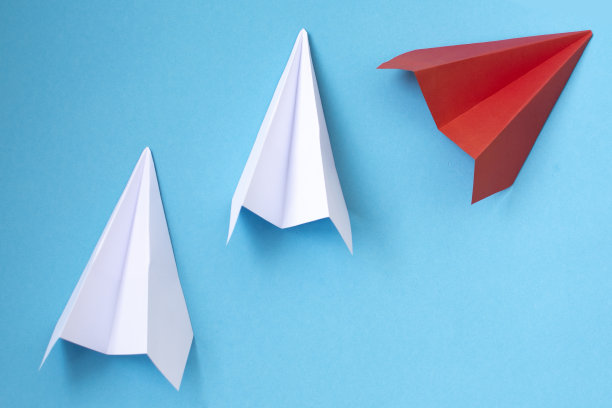 红色的纸飞机改变方向从白色的纸飞机在蓝色的背景。经营理念创新创意图片下载