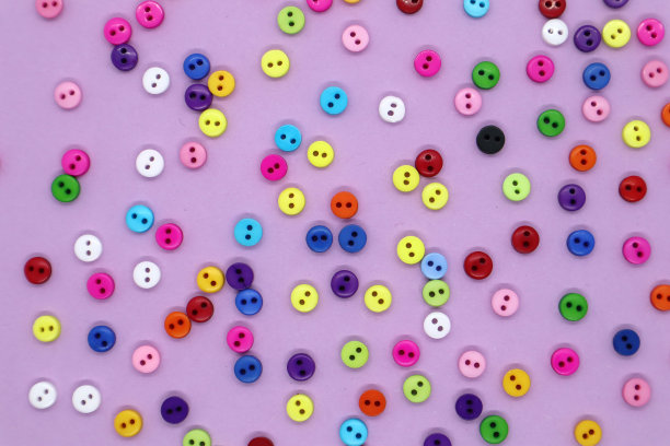 彩色缝纫按钮组合在粉红色的背景。图片下载