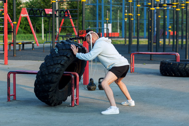 一个留着胡子，留着有趣发型的男人在做轮胎压压练习(磨边一个大轮胎)图片下载